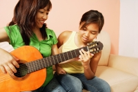Mother and daughter side by side, mother holding guitar - Alex Microstock02