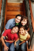 Family of four sitting on stairs, looking at camera, portrait - Alex Microstock02