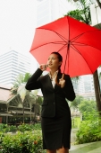 Business woman using mobile phone and carrying red umbrella - Alex Microstock02