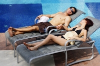  Couple lying on deck chairs by pool, holding hands - Alex Microstock02