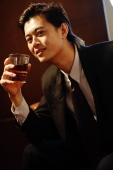 Businessman holding glass of whiskey, looking at camera - Alex Microstock02