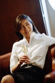 Woman sitting on sofa, holding glass on champagne, looking away - Alex Microstock02