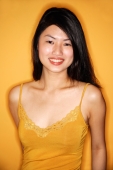 Young woman in yellow tank top standing against yellow wall - Alex Microstock02
