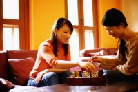 Young women sitting, playing chess in living room - Alex Microstock02