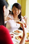 Young women eating pizza at cafe, over the shoulder view - Alex Microstock02