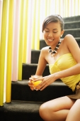 Young woman, sitting on steps, holding glass of juice - Alex Microstock02