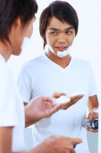 Young man with shaving foam on face, looking at reflection in mirror - Alex Microstock02