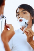 Young man with shaving foam on face, shaving - Alex Microstock02