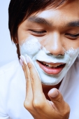 Young man applying shaving foam on face, looking down - Alex Microstock02
