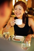 Couple in cafe, woman holding cup, smiling, over the shoulder view - Alex Microstock02