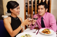 Couple in restaurant raising wine glasses for a toast - Alex Microstock02