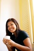 Young woman holding cup of coffee, looking at camera, smiling - Alex Microstock02