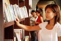 Young woman at bookstore, looking at books on shelf - Alex Microstock02
