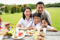 Family at picnic table, looking at camera, smiling - Alex Microstock02
