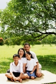 Family with two children, sitting on picnic mat, portrait - Alex Microstock02