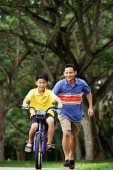 Father and son in park, son cycling, father running behind him - Alex Microstock02