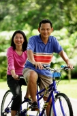 Couple on tandem bicycle, looking at camera - Alex Microstock02