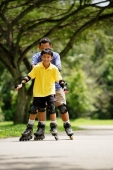 Father and son, in-line skating in park, father holding son from behind - Alex Microstock02