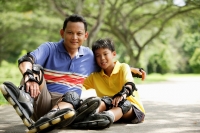 Father and son, sitting in park, wearing roller blades - Alex Microstock02