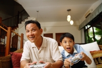 Father and son, sitting on sofa, playing with video games - Alex Microstock02