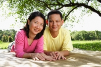 Couple lying on picnic mat, looking at camera, portrait - Alex Microstock02
