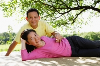 Couple on picnic mat, woman lying down, man sitting behind her - Alex Microstock02