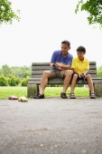 Father and son, sitting on bench, playing with remote control cars - Alex Microstock02