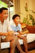 Father and son, sitting on sofa, playing with video games - Alex Microstock02
