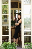 Young woman leaning on door, arms crossed, looking out - Alex Microstock02