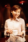 Woman holding cup and saucer, looking at camera - Alex Microstock02