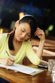 Young woman sitting at table with pen and paper, writing - Alex Microstock02