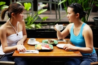 Two women sitting at table, having coffee and fruits - Alex Microstock02