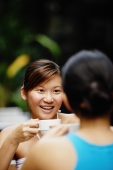 Woman holding cup, sitting across another woman - Alex Microstock02
