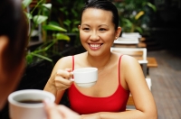 Woman holding cup, sitting across another woman, smiling - Alex Microstock02