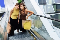 Young women, standing on escalator, looking up at camera - Alex Microstock02