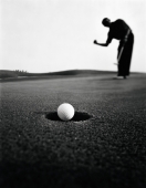 Asian golfer putting ball in hole - Martin Westlake
