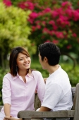 Couple sitting on park bench, looking at each other - Alex Microstock02