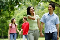 Couple holding hands and walking in park, people in the background - Alex Microstock02