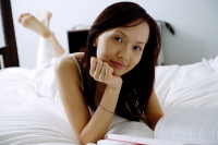Young woman lying on bed, hand on chin, looking at camera - Alex Microstock02