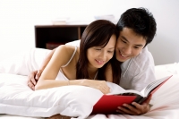 Couple lying on bed, reading book - Alex Microstock02