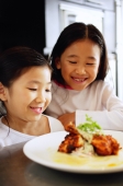  Two girls looking at a plate of food, smiling - Alex Microstock02