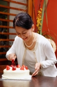 Mature woman cutting birthday cake, smiling - Alex Microstock02