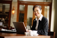 Businesswoman using laptop, smiling at camera - Alex Mares-Manton