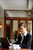 Businesswoman sitting at table using laptop - Alex Mares-Manton