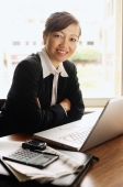 Businesswoman sitting at table, laptop open, smiling at camera - Alex Mares-Manton