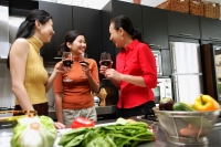 Three women in kitchen, holding wine glasses, talking - Alex Microstock02