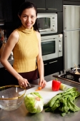 Woman in kitchen, cutting vegetables, smiling at camera - Alex Microstock02