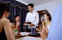 Friends at dining table, man giving cake to woman - Alex Microstock02