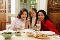 Three women sitting at restaurant table, smiling at camera - Alex Microstock02