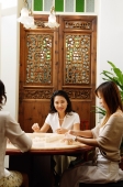 Three women spending time together playing mahjong - Alex Microstock02